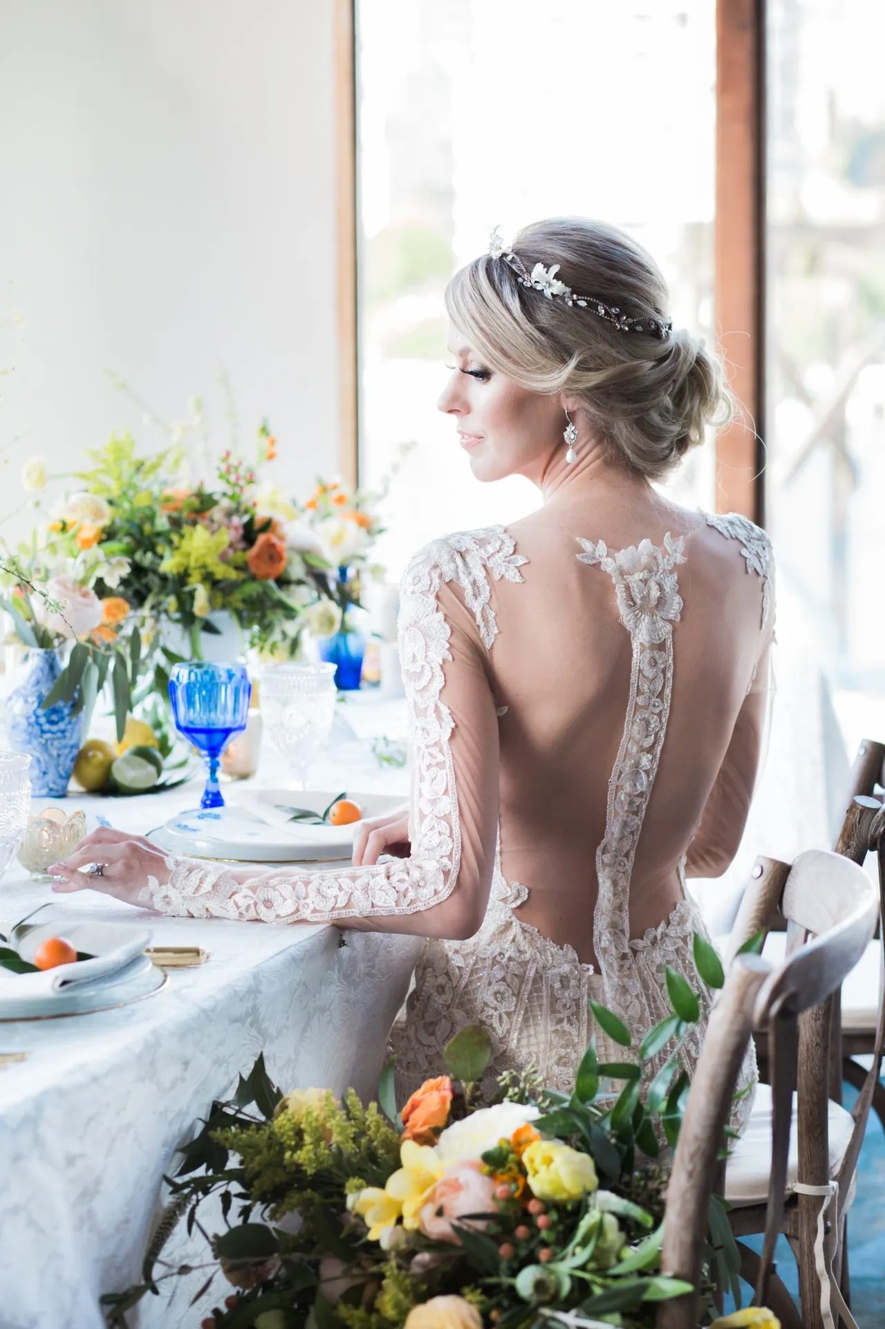 The open lace back of the gown, with citrus and blue glassware on the table.